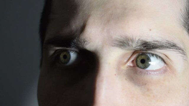 Scared man wakes up, hears strange noises at home at night and looks all around. Unsafe home, insecurity concept