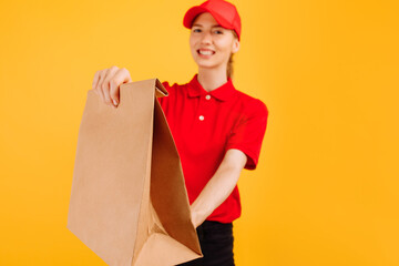 Deliveryman in red uniform holds paper bag with food, Female employee works as a courier