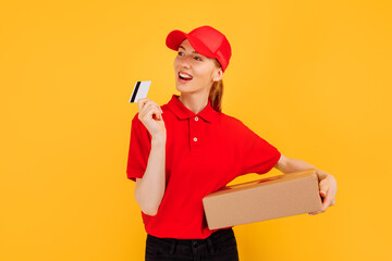 Courier, in red uniform, delivery employee holds a cardboard box and a credit card on a yellow background