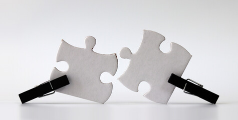 Black wooden tongs and two white puzzles. Puzzle pieces and business concepts.
