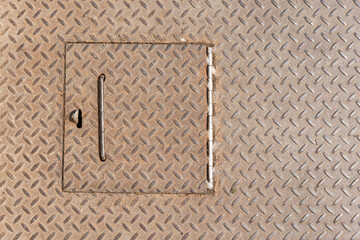 close up of a trap door on an anti-slip textured metal plate