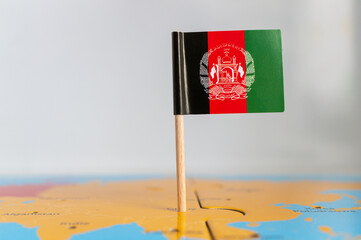 Small rotated flag of Afghanistan on a wooden stick fixed on the globe