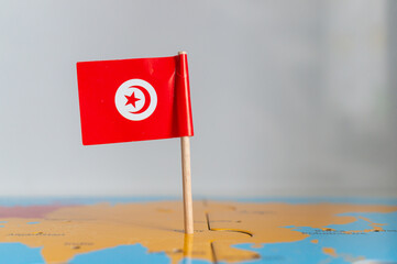 Small rotated flag of Tunisia on a wooden stick fixed on the globe