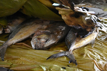 A delicious traditional grilled fish on a banana leaf by using a bonfire at camping activities.