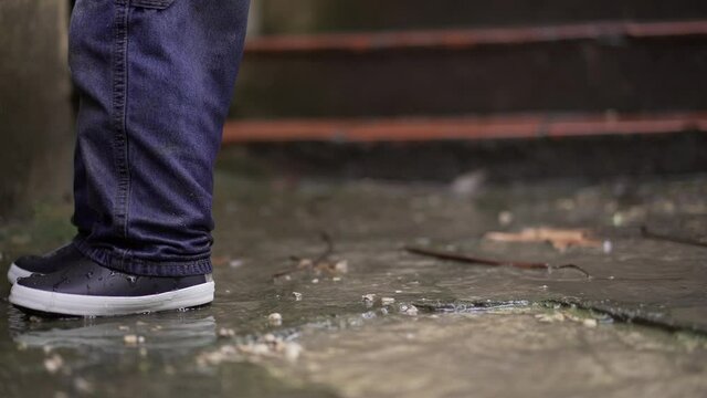 Little baby toddler jumping into water puddle