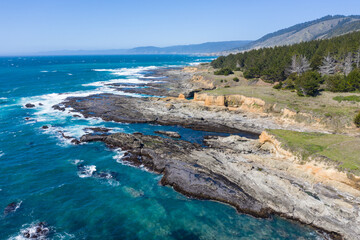 The Pacific Ocean crashes onto the rugged shore of Northern California in Mendocino on a beautiful day. This region is known for its scenic mountains, forests, and coastline.
