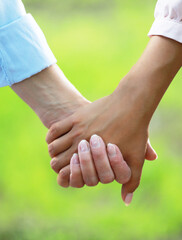 Elderly Mother holding a hand of her adult daughter in summer day outdoors