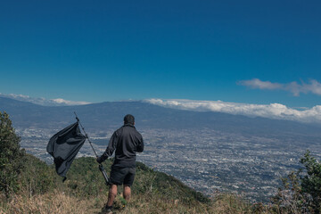 Man with a black flag contemplating the capital city of San José, Costa Rica in the middle of a...
