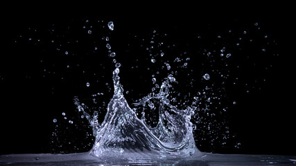 水面に氷を落とした瞬間の水しぶきのテクスチャー。 黒い背景