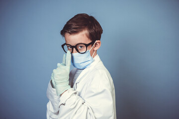 cool boy with mouth guard, black glasses and rubber gloves with white lab coat or doctor coat on blue background in the studio