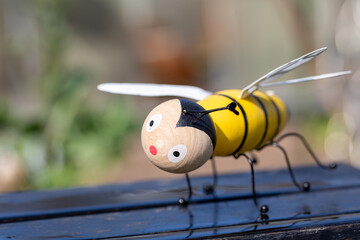 Bee made of wood in unusual rainy weather in spring in search of honey with astonished expression