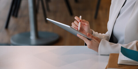 Close up businesswoman holds pen stylus drawing on digital tablet on workplace