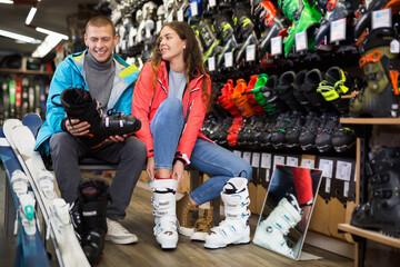 Man and woman together choosing ski boots in sport goods store