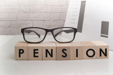 PENSION word about the concept of blocks standing on a white table surface, glasses on cubes