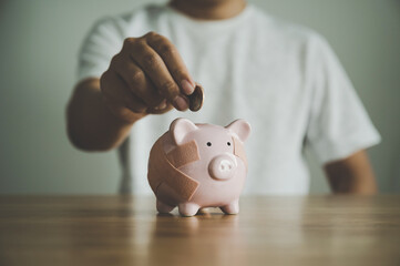Hand putting coin in piggy bank on wooden table. Concept of save money and finance business...