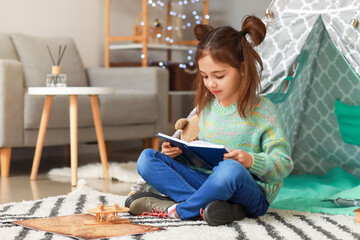 Cute little girl reading book at home