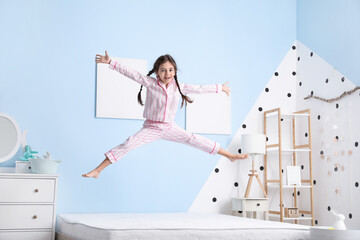 Funny little girl jumping on bed