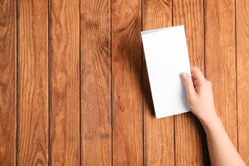Obraz premium Hand with blank brochure on wooden background