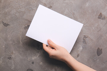 Hand with blank brochure on grey background