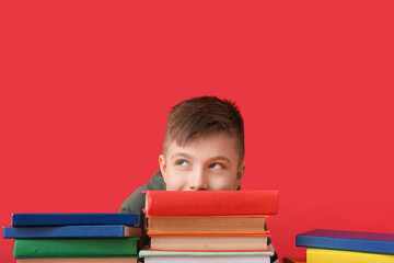 Cute little boy with many books on color background
