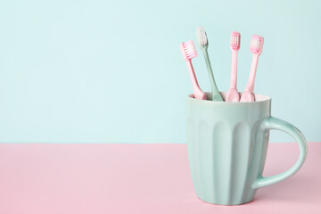 Cup with tooth brushes on color background