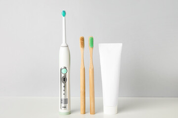 Different tooth brushes and paste on light background