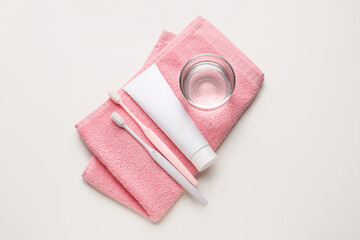 Tooth brushes, paste, glass of water and towel on white background