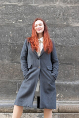 Portrait of a young woman in a coat on dark wall background.