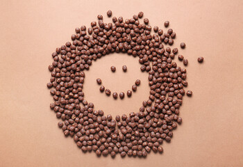 Smile made of chocolate corn balls on color background