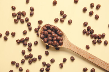 Spoon with chocolate corn balls on color background