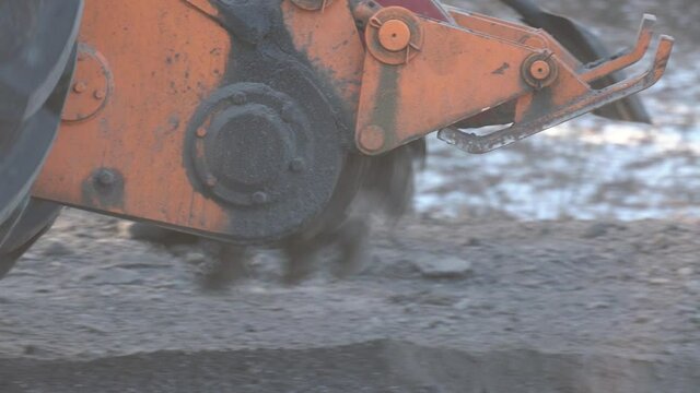 Saw for cutting asphalt mounted on a tractor. Road milling machine cuts the old asphalt. Road repair. Destruction of the road surface. The cutter cuts a layer of asphalt. Pieces of stone fly apart. 
