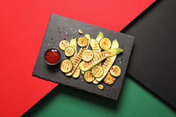 Board with tasty grilled squashes on color background