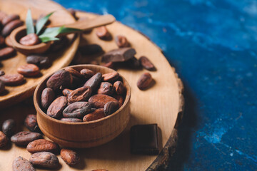 Bowl with cocoa beans on color background