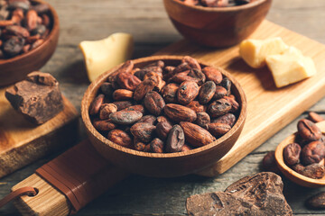 Bowl with cocoa beans on wooden background