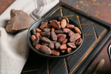 Bowl with cocoa beans on grunge background