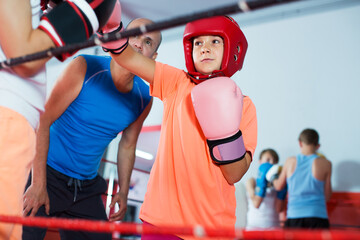 Fototapeta na wymiar Group of children exercising with mentor on boxing ring at gym