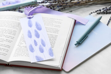 Book with bookmark and stationery on light background