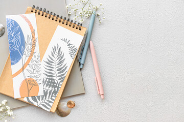 Notebooks with bookmarks and flowers on light background