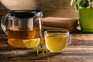 Cup of green tea and teapot on wooden background
