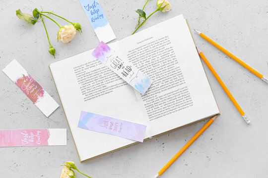 Book with bookmarks and flowers on light background