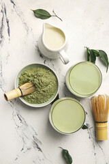Composition with glasses of matcha tea and powder on light background