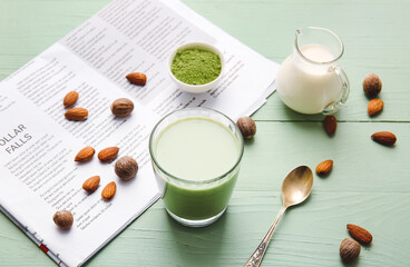 Composition with glass of matcha tea, powder and milk on color wooden background