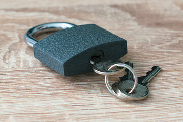 iron padlock with keys in the keyhole on a wooden surface concept prohibition security restriction