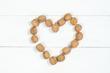 heart of whole walnuts on a light wooden background. Healthy food nuts.