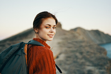 woman climbs the mountains along the path and a backpack on her back side view