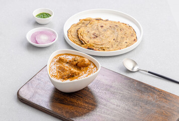 butter chicken, an Indian creamy chicken gravy served in a white bowl with roti or naan