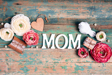 Festive background with peonies flowers, gifts and word mom on shabby wooden turquoise boards.