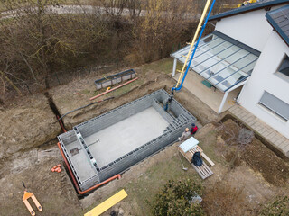 aerial drone shot of pool construction site, form blocks being filled with concrete
