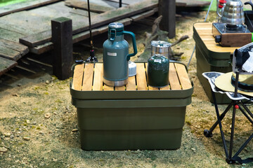 Kettle, stove and camping chairs outside the tent at campsite.