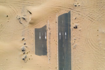 Birds eye view of a sand covered empty road in the Dubai desert